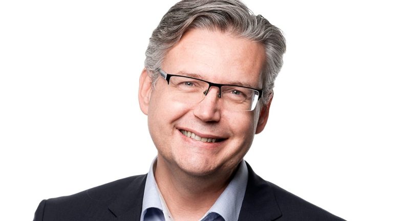 Porträttbild av man med kavaj och blå skjorta