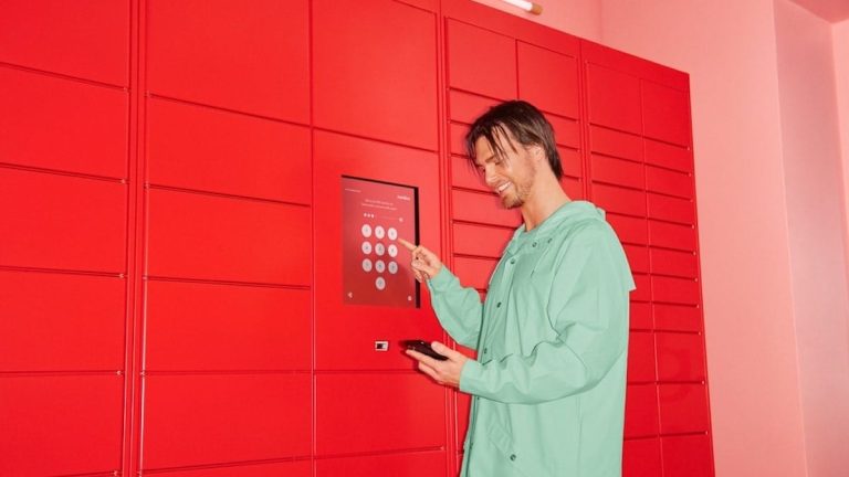 En ung man hämtar ut paket från en Instabox-anläggning.