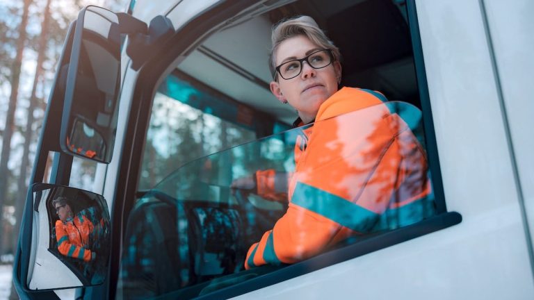 Lastbilschaufför i lastbil tittar snett bakåt