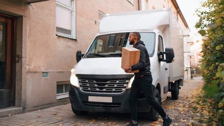 Ett bud med paket framför en transportbil