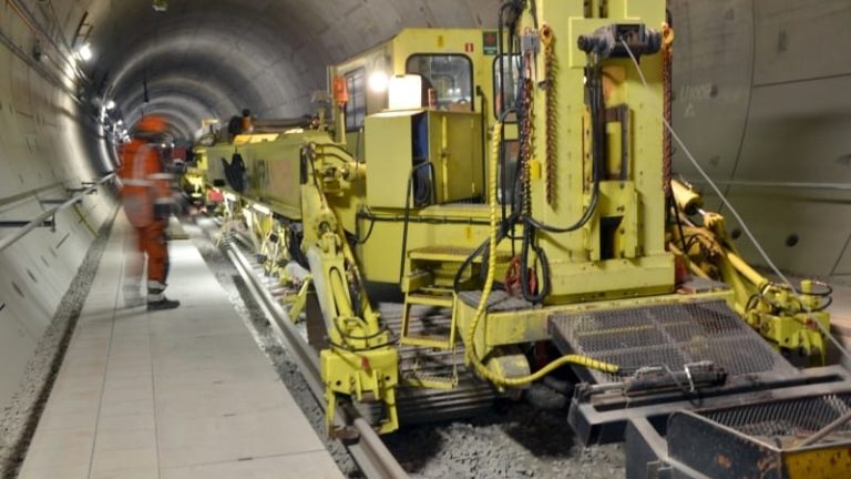 Rälsläggningsmaskinen SVM1000 tar tag i rälen fäster den i sliprarna. Den har det de senaste veckorna lagt upp till 1200 meter järnväg per dygn i Hallandsåstunneln.