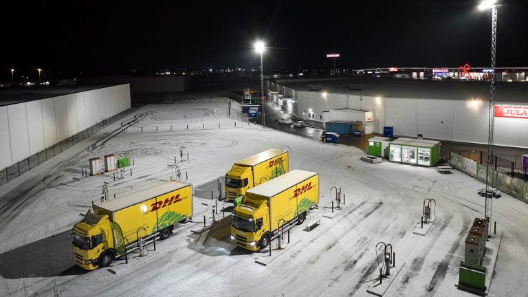 Tre lastbilar på en laddstation Tre lastbilar på en laddstation