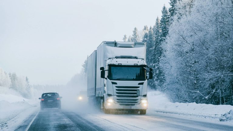 Lastbil på snöig väg i vinterlands