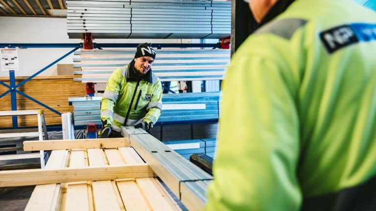 Arbetare hanterar träskivor i lagerbyggnad