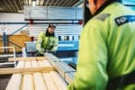 Arbetare hanterar träskivor i lagerbyggnad